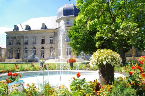 Jets d'eaux dans le parc fleuri et arboré de la mairie avec ça façade en arrière-plan.