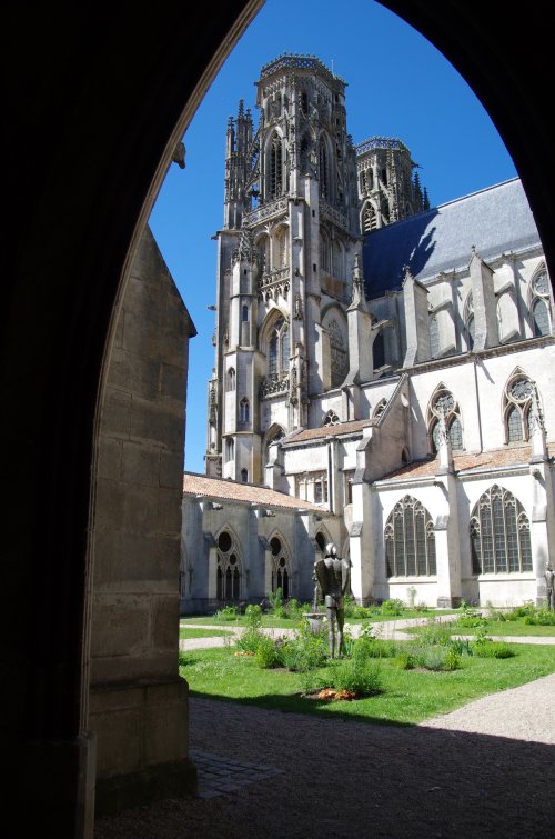Vue de la tour nord de la cathédrale à travers une arcade en ogive du cloitre. 